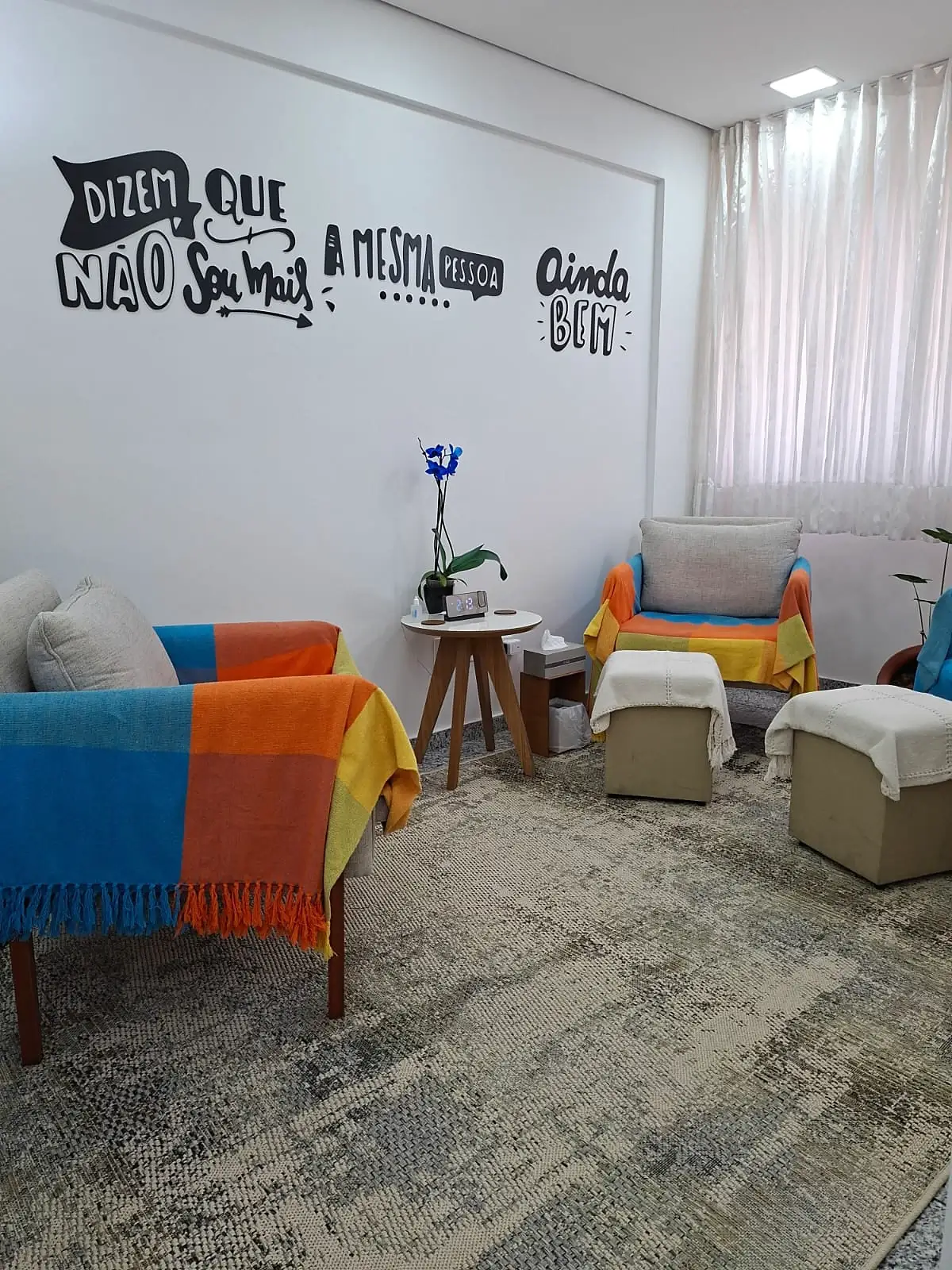Consultório com poltronas coloridas e mensagem na parede